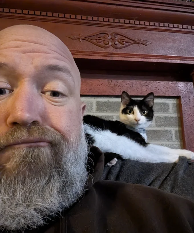 Anthony Sullivan, with his black-and-white cat perched on his shoulder